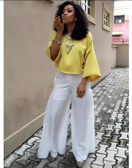 Blowing kisses in a silk yellow blouse and palazzo trousers